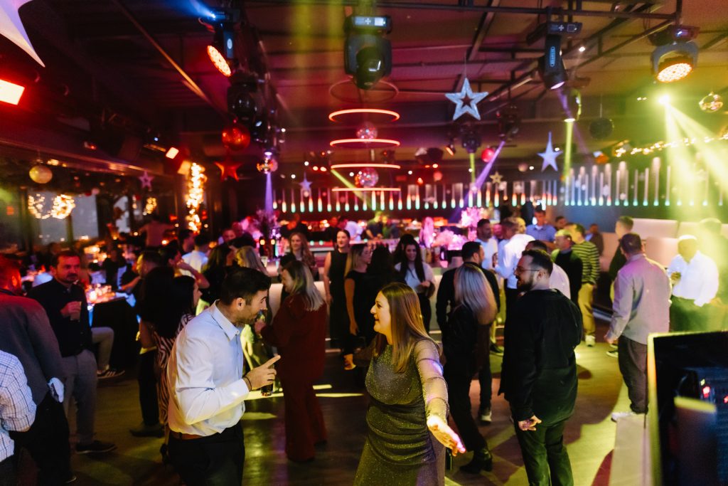Colleagues socializing at a corporate Christmas party with festive lighting